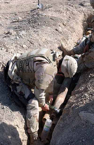 U.S. Air Force Explosive Ordnance Disposal tech placing C-4 explosives on munitions in a trench before exploding; Oct. 2, 2005.
