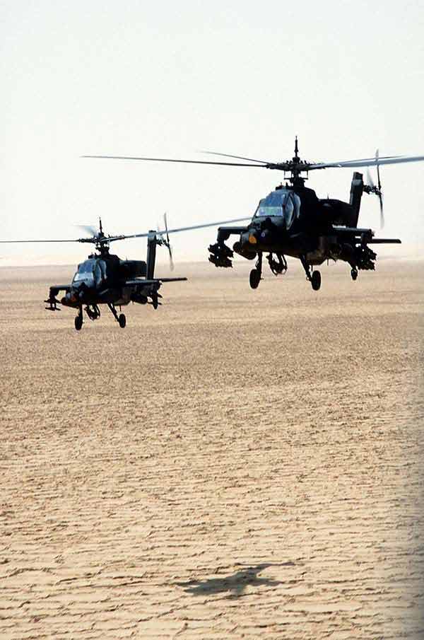 AH-64A Apache helicopters pass over the desert during Operation Desert Shield. Each helicopter is armed with a pair of 19-round launchers for 2.75-inch folding-fin aerial rockets; the helicopter at right is also carrying eight AGM-114 Hellfire missiles.