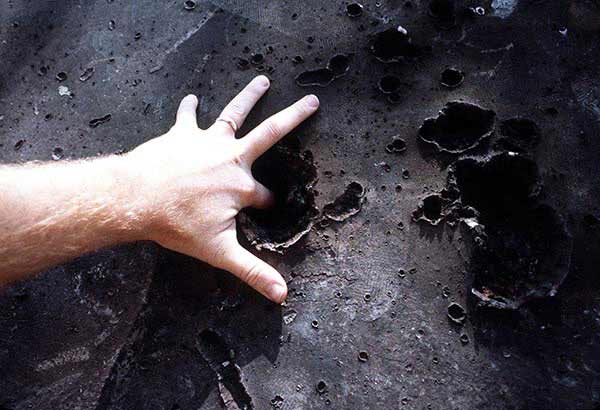 A close-up view of explosion holes on an armor-plated steel piece. The penetration test of a copper experimental explosive projectile takes place at an armament laboratory near the base, 5/1/1980. Eglin Air Force Base, FL.