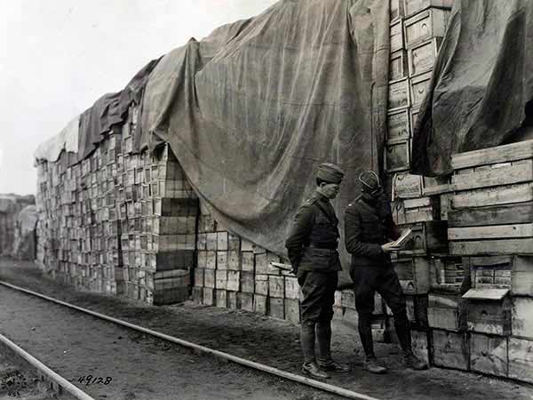 Ten thousand cases of hard bread stored in open at American Embarkation Center. The bread, which is packed in tins, is stored on the outside of the pile while that in the center and less exposed is packed in carton packages. The officers are, 1st Lt. E.E. Hall, Q.M.C., and 1st Lt. P.C. Hunter, Inf. Le Mans, Sarthe, France.