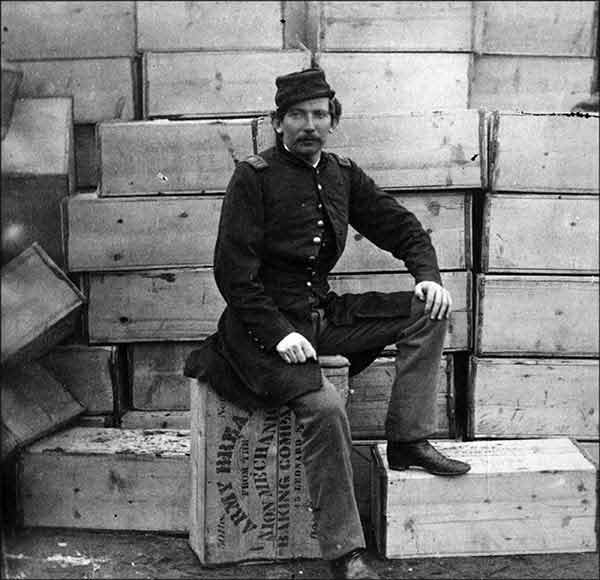 A Union Soldier sitting on crates of hardtack.
